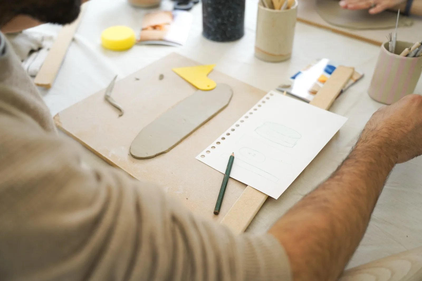 Découpe d’une plaque de terre pendant un atelier, outils et gabarits posés sur la table