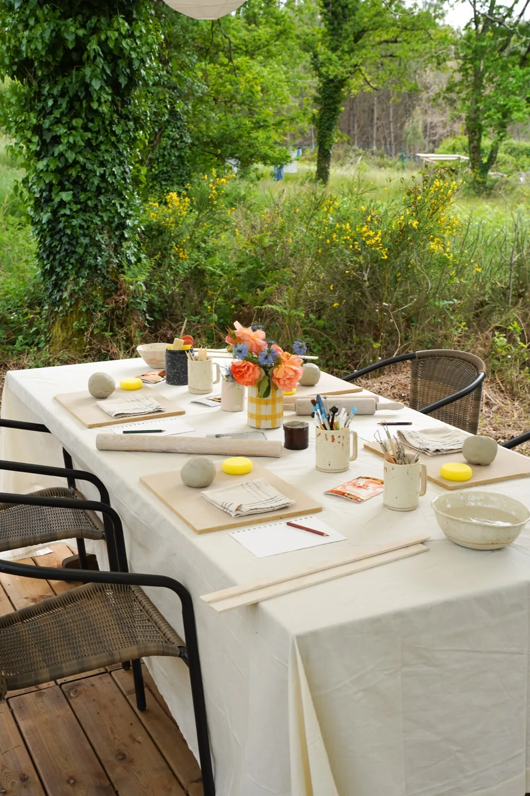 Table d’atelier dressée en extérieur, planches, outils et bouquet posés à chaque place