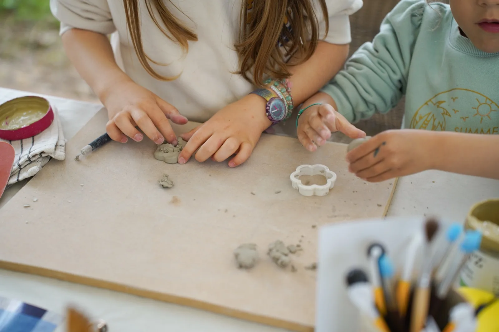 Des enfants modèlent la terre à plusieurs autour d’une table d’atelier