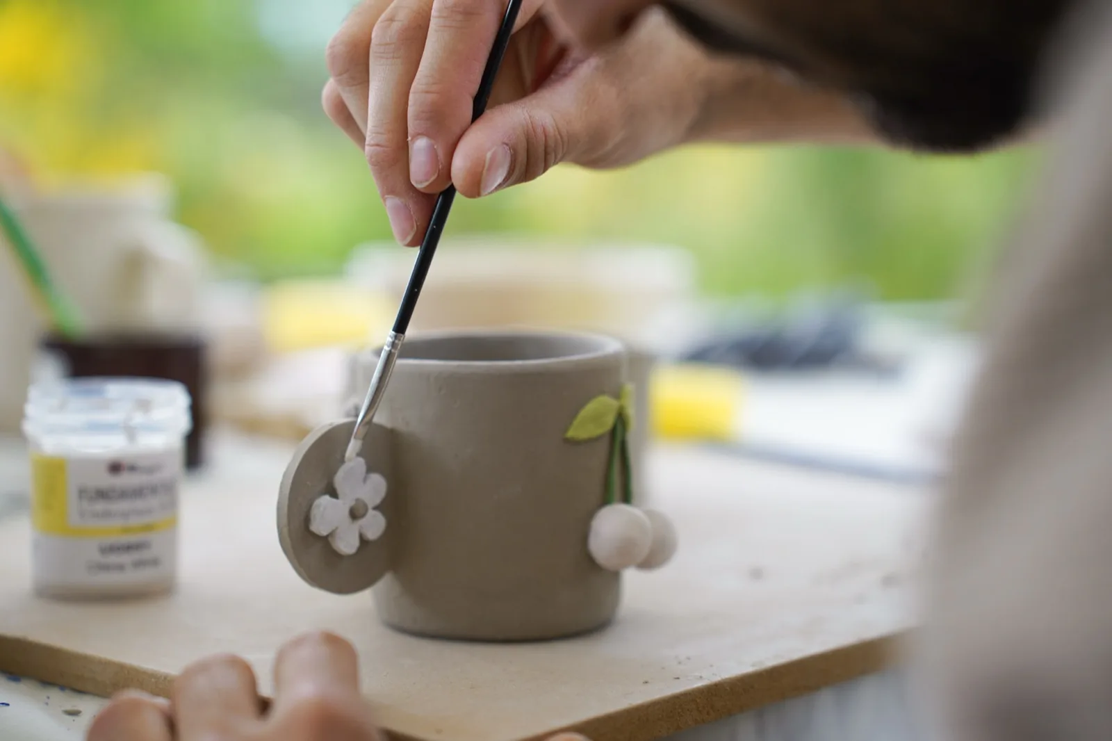 Décoration au pinceau d’un mug en terre orné de fleurs modelées