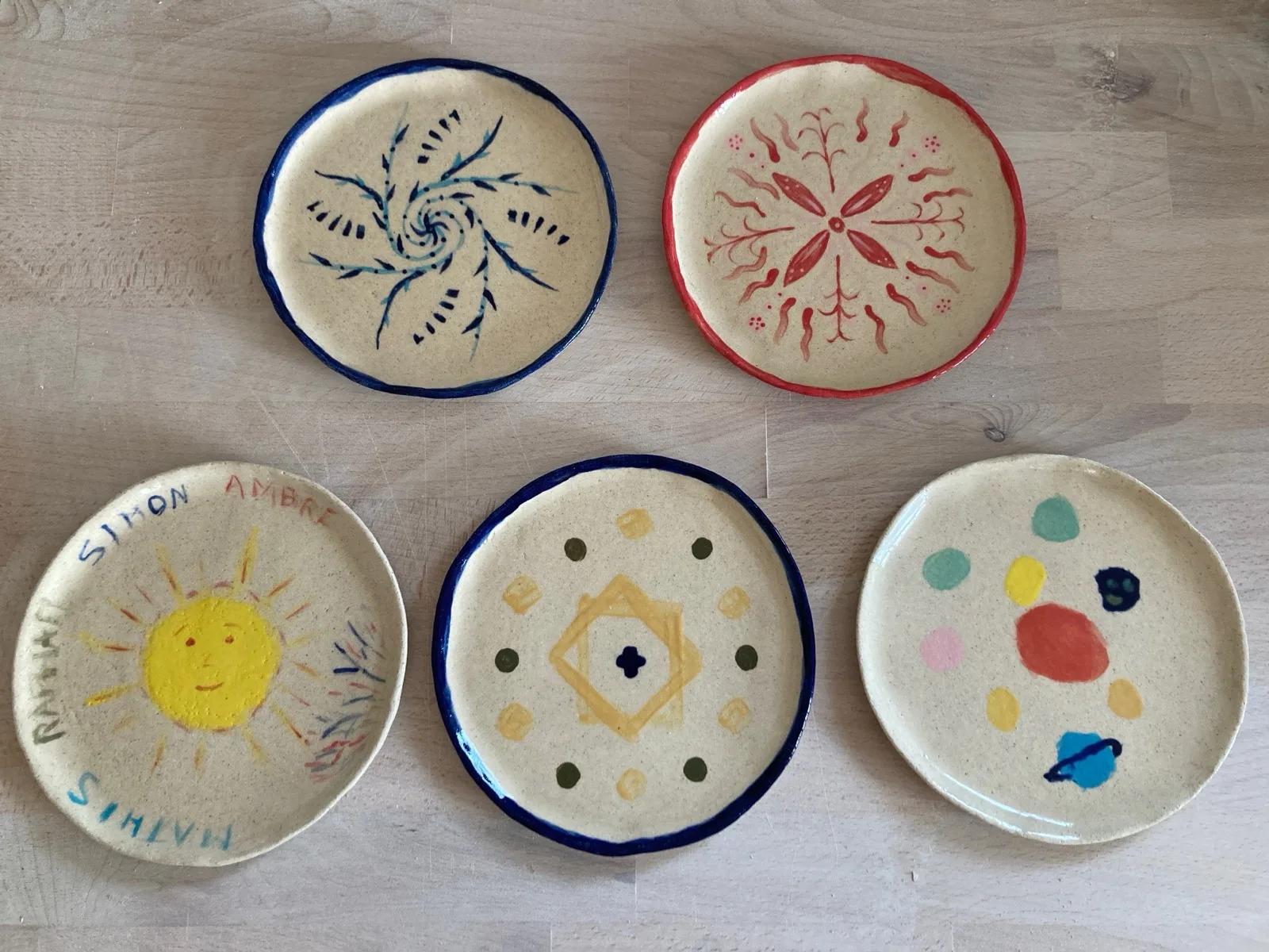 Cinq assiettes en céramique décorées à la main et cuites, posées côte à côte